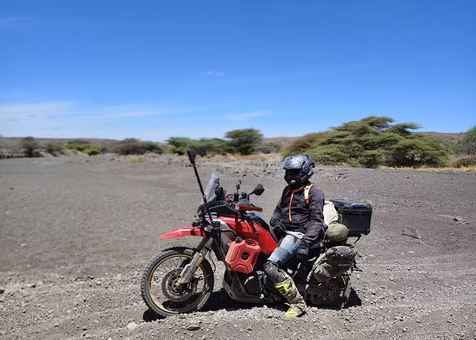Rider and motorcycle on volcanic gravel in the northern Kenya desert
